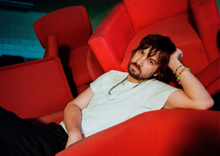 Artist Tame Impala on a red chairx